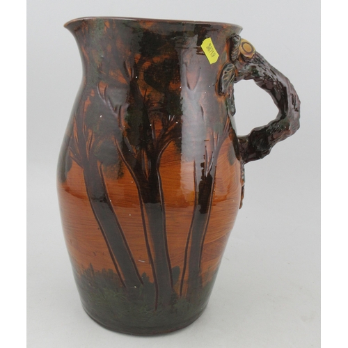 283 - A large Longward pottery jug, decorated all round with trees and having a branch handle, signed to b... 