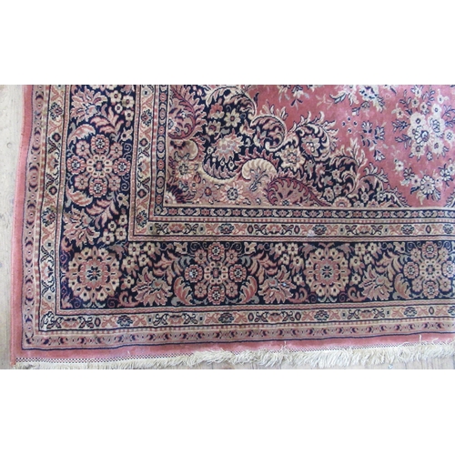 64 - A modern rug, decorated with flowers and scrolling leaves to a peach ground, 80ins x 110ins