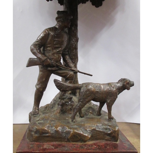 165 - A pressed metal table lamp, formed as a huntsman carrying a gun with hound, under a tree, height 15i... 