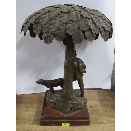 165 - A pressed metal table lamp, formed as a huntsman carrying a gun with hound, under a tree, height 15i... 