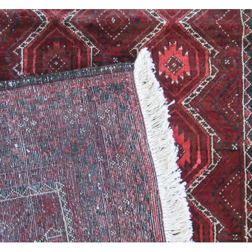 83 - An Eastern design red ground rug, with repeating motifs to the field, 72ins x 41ins