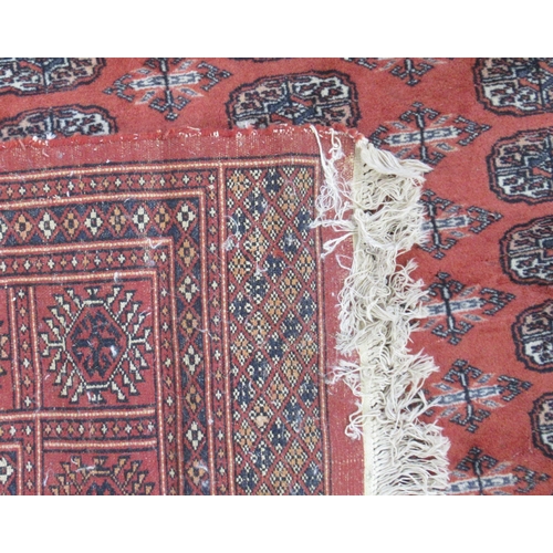 87 - An Eastern design rug, the field with repeating motifs and a red ground, 101ins x 73ins