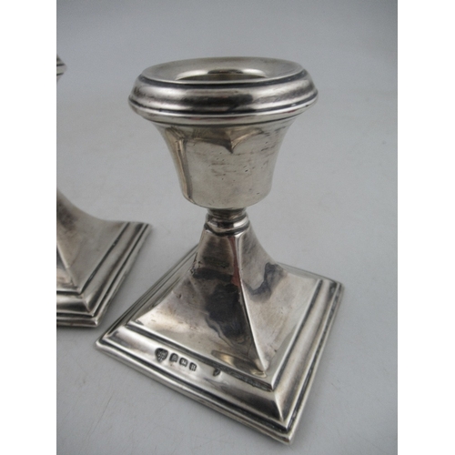 231 - A pair of silver dwarf candlesticks, on square bases, together with a glass bottle with silver screw... 