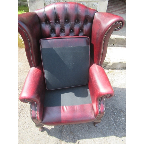 31 - A Thomas Lloyd red leather wing back armchair, with deep buttoned back, raised on claw on ball feet