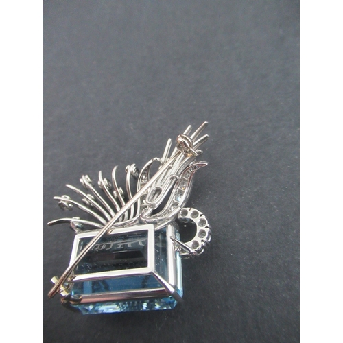 313 - A white gold aquamarine and diamond asymmetric brooch, claw set emerald cut aquamarine, with fan spr... 