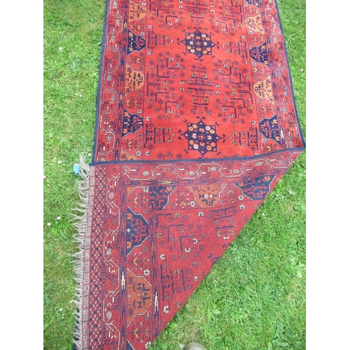 87 - An Eastern design rug/runner, decorated with geometric design to a red ground, 110ins x 40ins