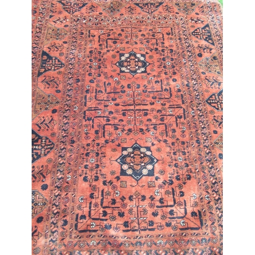 90 - An Eastern rug, with geometric decoration to a red ground, 75ins x 52ins