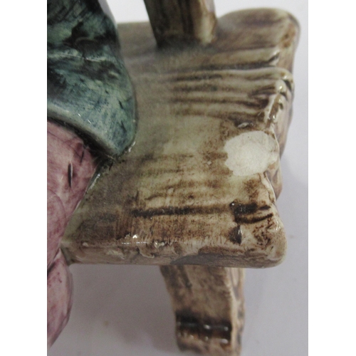 133 - A pair of Continental pottery models, of a boy and a girl seated on benches, height 6ins