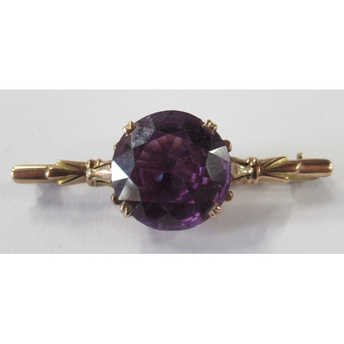 210 - A gold bar brooch, set with a synthetic colour changing sapphire