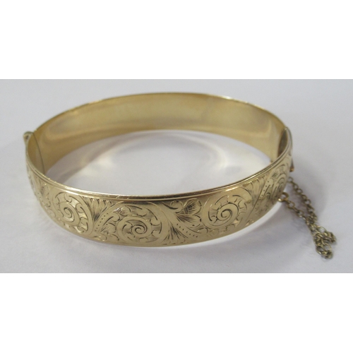 223 - A rolled gold hinged bracelet, with engraved decoration