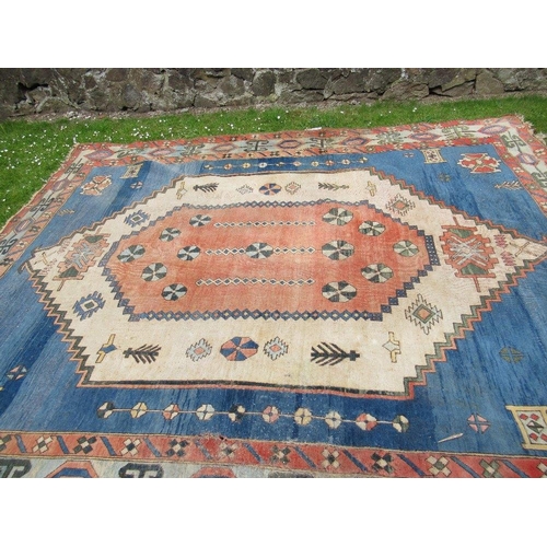 66 - A large carpet with a central blue, salmon pink and beige ground decorated with motifs with a simila... 