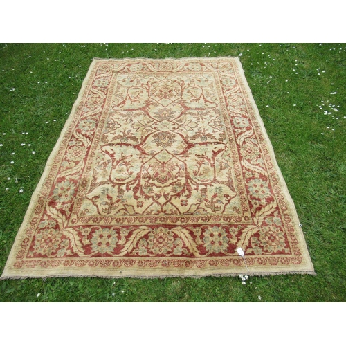 67 - An Eastern design carpet with a light brown central field with foliage and a similar boarder on a re... 