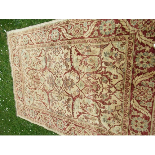 67 - An Eastern design carpet with a light brown central field with foliage and a similar boarder on a re... 