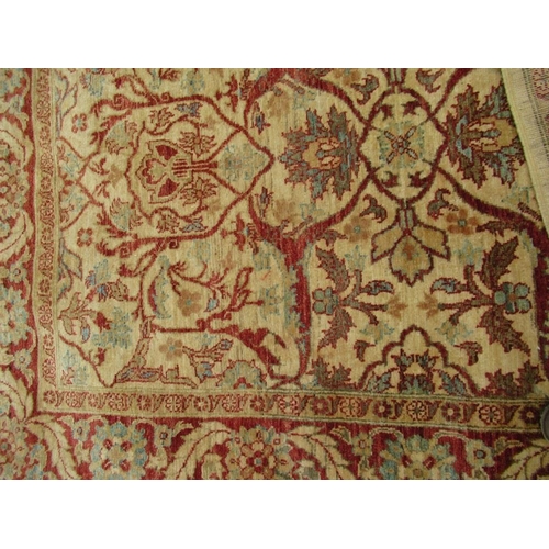 67 - An Eastern design carpet with a light brown central field with foliage and a similar boarder on a re... 