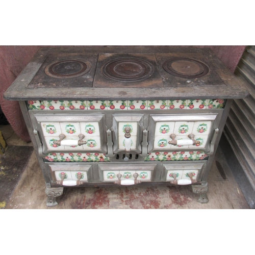 94 - A French cast iron stove, decorated with tiles, with cooking plates to the top, oven to the front an... 