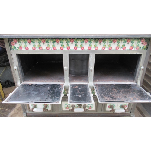 94 - A French cast iron stove, decorated with tiles, with cooking plates to the top, oven to the front an... 