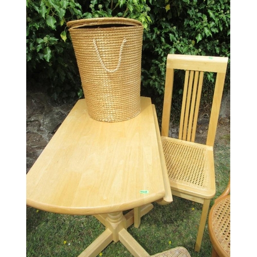 61 - A drop leaf kitchen table and two chairs together with a linen basket and a wicker shelf unit