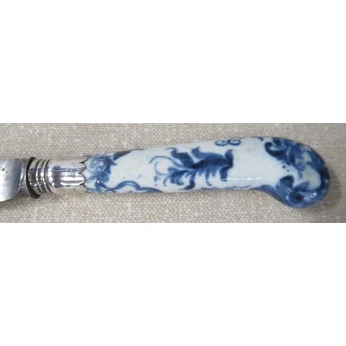 218 - An 18th century pistol grip dinner knife, with porcelain handle decorated in blue and white, the ste... 