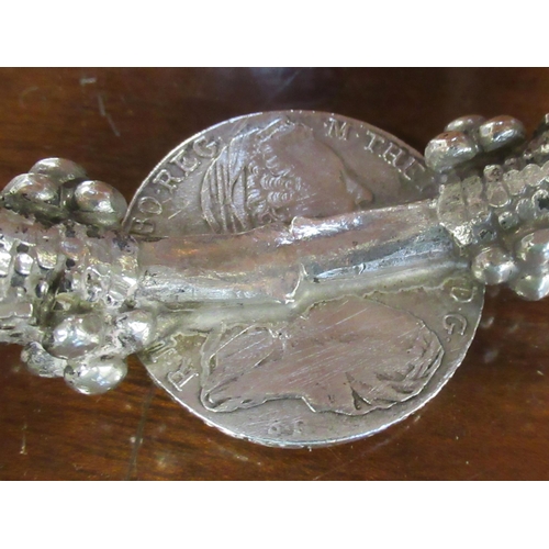 393 - A silver coloured bangle, set with a coin