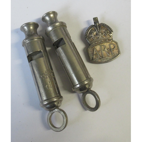 209 - ARP, two J Hudson & Co whistles, together with a badge