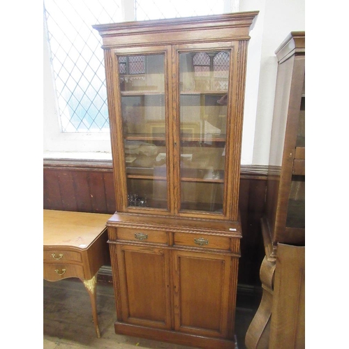 3 - An oak cabinet with glazed upper section over covered doors, width 36ins, height 83ins