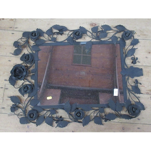 521 - A wall mirror, the black metal frame decorated with roses and leaves