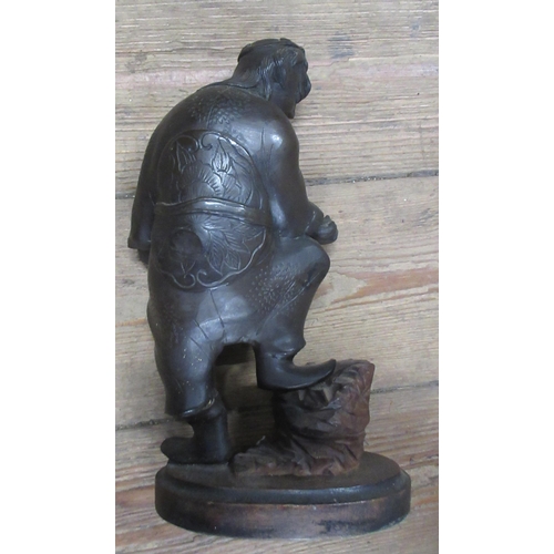 206 - An Eastern metal figure, of a man with his foot on a stump, on wooden base