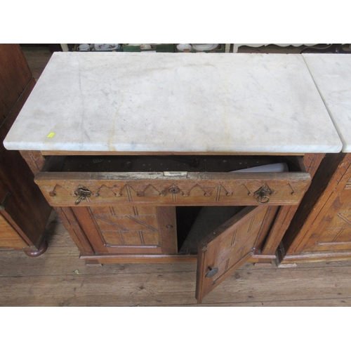 29 - A pair of Edwardian oak and marble topped cabinets, with Gothic style decoration, having a frieze dr... 