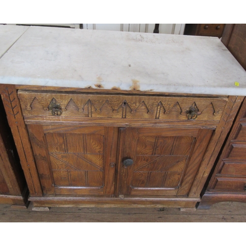 29 - A pair of Edwardian oak and marble topped cabinets, with Gothic style decoration, having a frieze dr... 