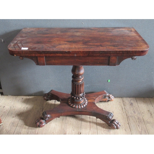 32 - A 19th century rosewood fold over games table, on turned column, to platform base with paw feet, wid... 