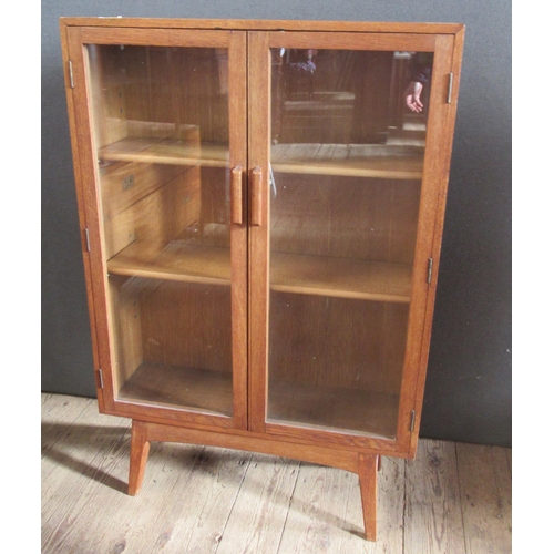 35 - An oak Arts & Crafts style two door cabinet, with glazed doors and adjustable shelves, 30ins x 9.5in... 