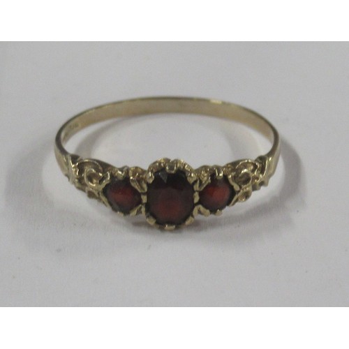427 - A 9ct graduated three stone garnet set ring, cast scroll shoulders, hallmark indistinct