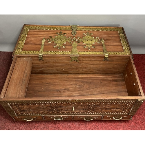 199 - A nicely carved rosewood trunk of Oriental origin having brass decoration and hardware, with interna... 