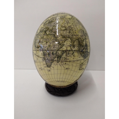 113 - Ostrich egg on plinth, decorated with African animal scene to the front and world map on the reverse... 