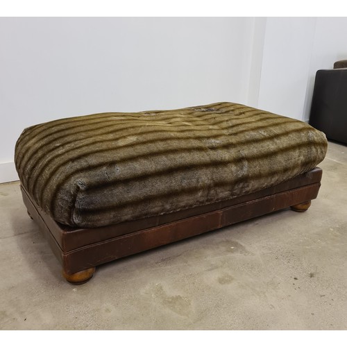 32 - A large leather and faux fur pouffe footstool. Measuring 44 (h) x 125 (w) x 77 (d) cm.