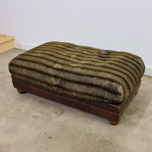 32 - A large leather and faux fur pouffe footstool. Measuring 44 (h) x 125 (w) x 77 (d) cm.