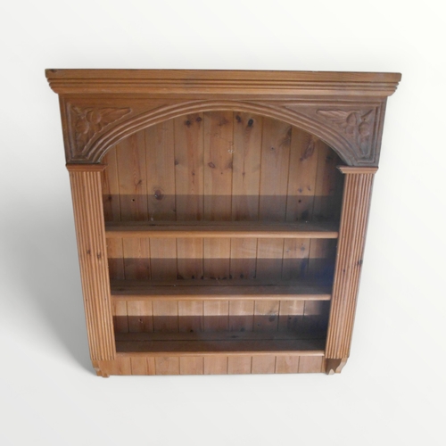 215 - A pine set of hanging shelves with a carved and reeded framework and an arched open front. 100 x 84c... 