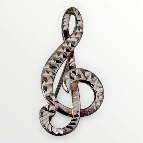 67 - A faceted silver brooch in the form of a treble clef. Shipping group (A).