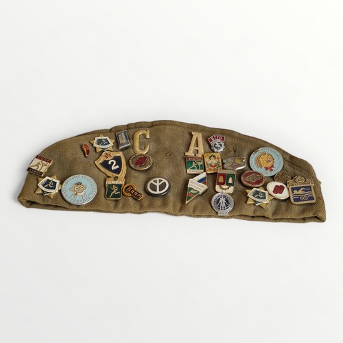 74 - Military hat having numerous Soviet badges and patches applied. Shipping group (A).