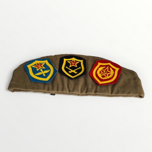 74 - Military hat having numerous Soviet badges and patches applied. Shipping group (A).