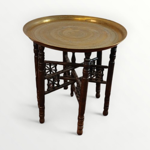 148 - Middle Eastern brass tray top table 56cm diameter supported on a folding six legged base, 54cm high.