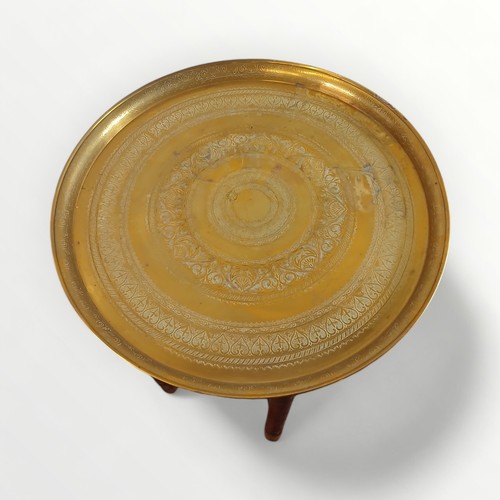 148 - Middle Eastern brass tray top table 56cm diameter supported on a folding six legged base, 54cm high.