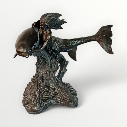 289 - Cast figure of a mermaid with a dolphin on a rocky base, 31cm high. Shipping group (A).