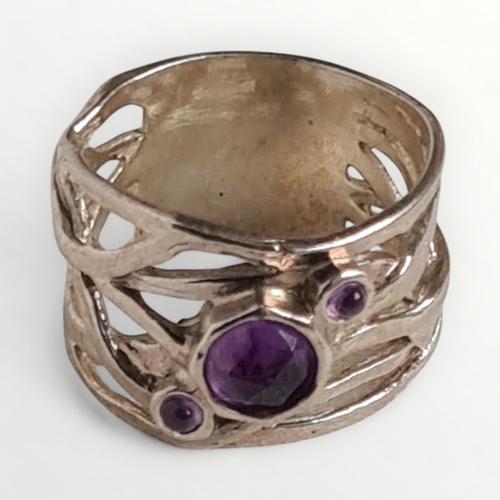 38 - A wide 925 silver ring set with three amethyst stones. Shipping group (A).