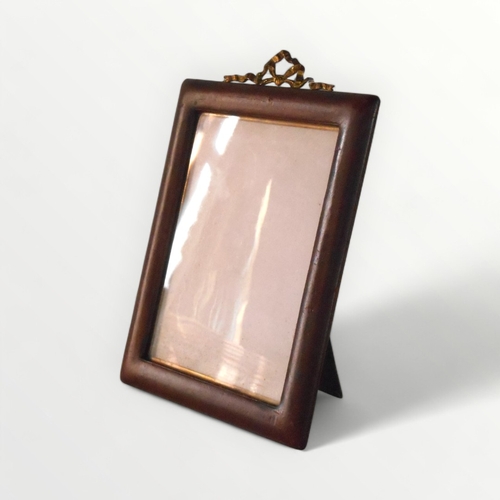 129 - A vintage leather covered easel back photo frame, having gilt 'bow' crest, to take a 9