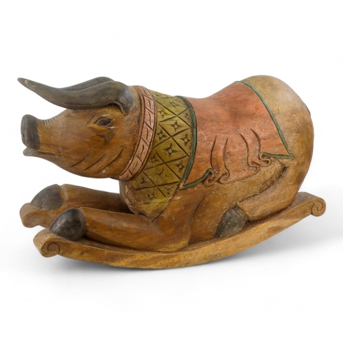 23 - A polychrome painted hardwood rocking pig - the squatting hog with a diaper carved panel on rockers,... 