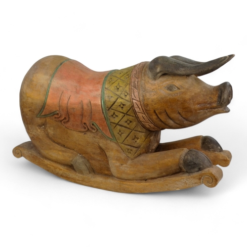 23 - A polychrome painted hardwood rocking pig - the squatting hog with a diaper carved panel on rockers,... 