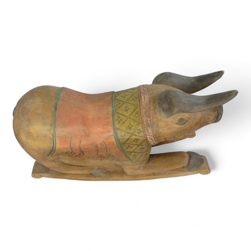 23 - A polychrome painted hardwood rocking pig - the squatting hog with a diaper carved panel on rockers,... 