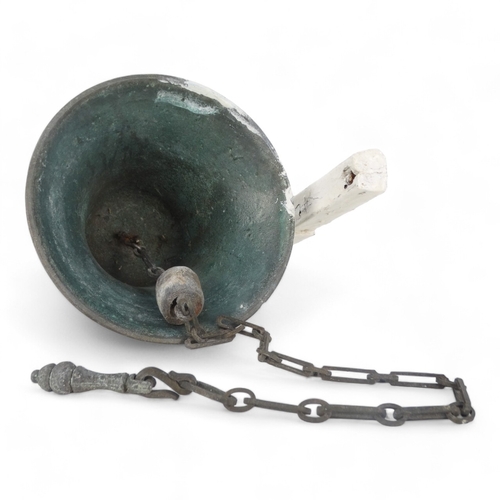 24 - A vintage bronze bell - with a white painted bracket, 18cm high.