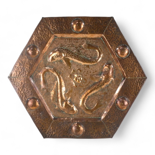 5 - An early 20th century copper wall plaque - hexagonal repousse decorated with three fish, 34cm wide.